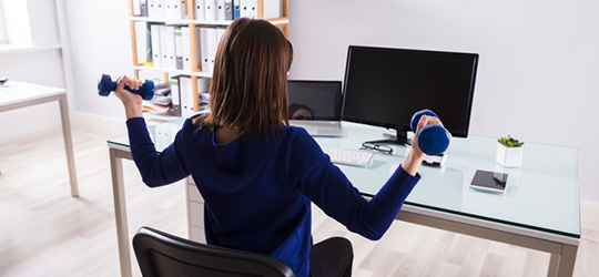 woman lifting weights at desk