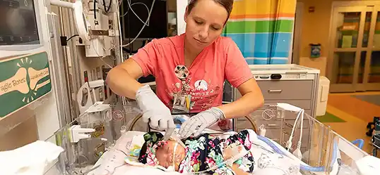 NICU nurse checking lines on baby