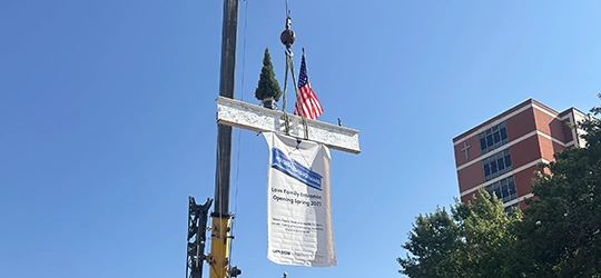 Hospital final beam with evergreen tree and U.S. flag.