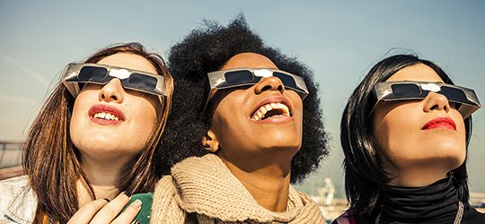 people in eclipse glasses looking at the solar eclipse