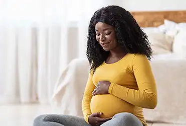Pregnant woman smiling an holding belly