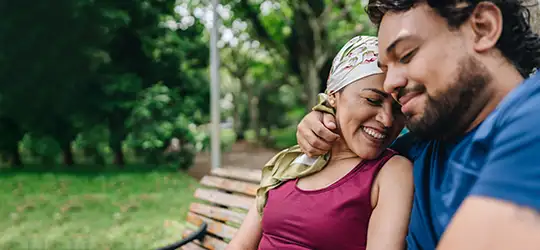 woman with cancer sitting on park bench with husband