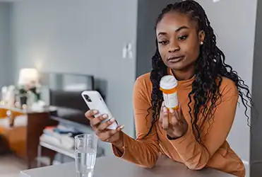 young woman refilling prescription via MyChart app on her phone