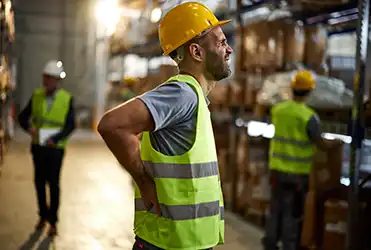 man in hard hat clutching back in pain