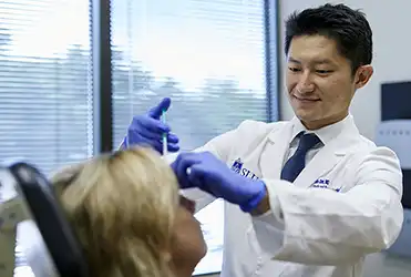Facial plastic and reconstructive surgeon Dr. Collin Chen works with a patient