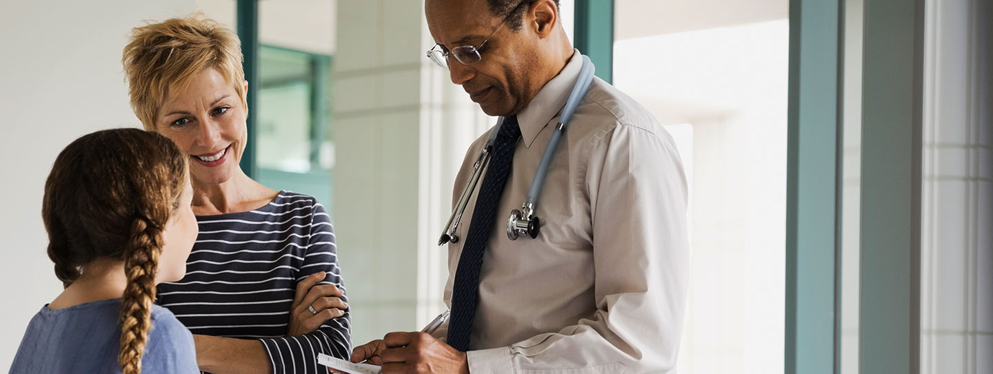 physician speaking to young girl and mom