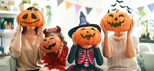 mom, grandma, and kids posing with jack-o-lanterns for halloween