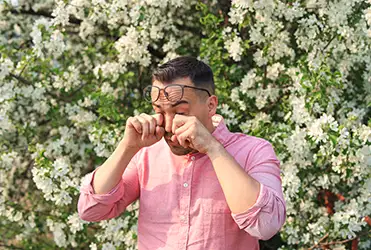 man rubbing his eyes due to allergies