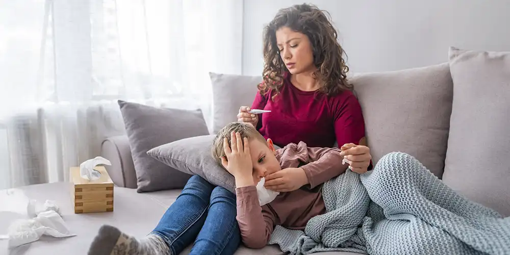 mom taking temperature of son exhibiting cold-like symptoms