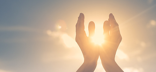 hands cradling sun in the sky