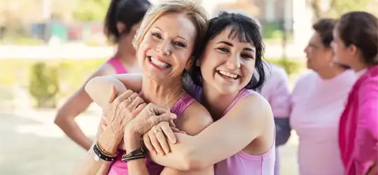 women hugging at breast cancer awareness event