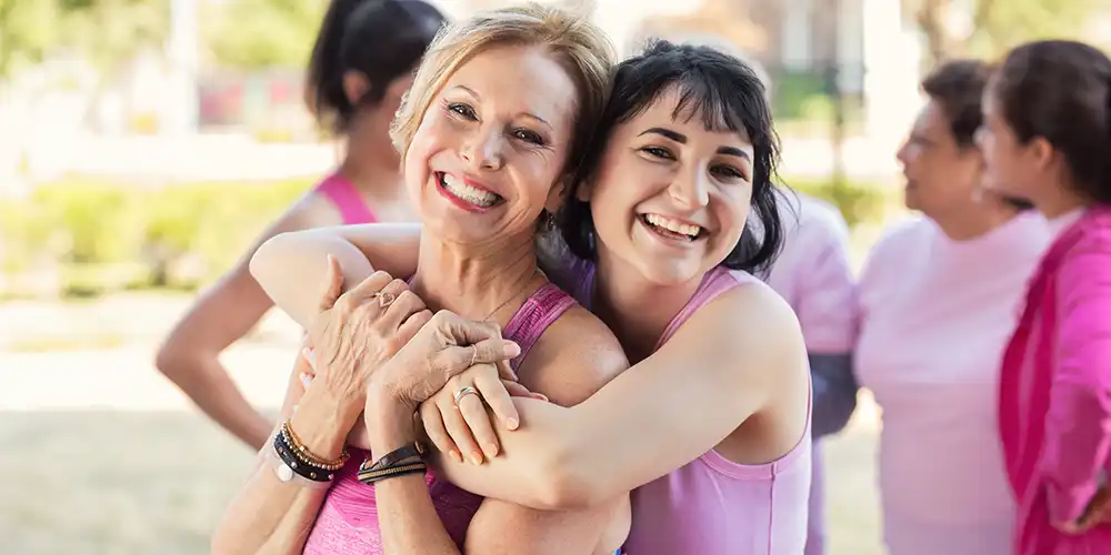 women hugging at a breast cancer awareness event