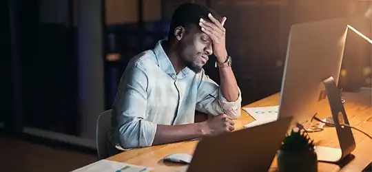 Man sitting in front of a computer, clearly stressed