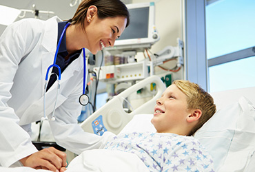 Nurse with young patient in hospital bed