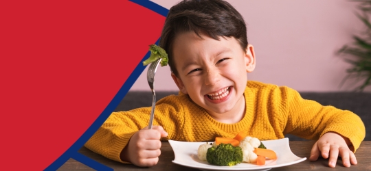 young boy spearing broccoli on fork
