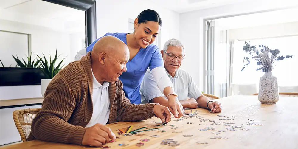 staff at assisted living facility helping two seniors work on a puzzle