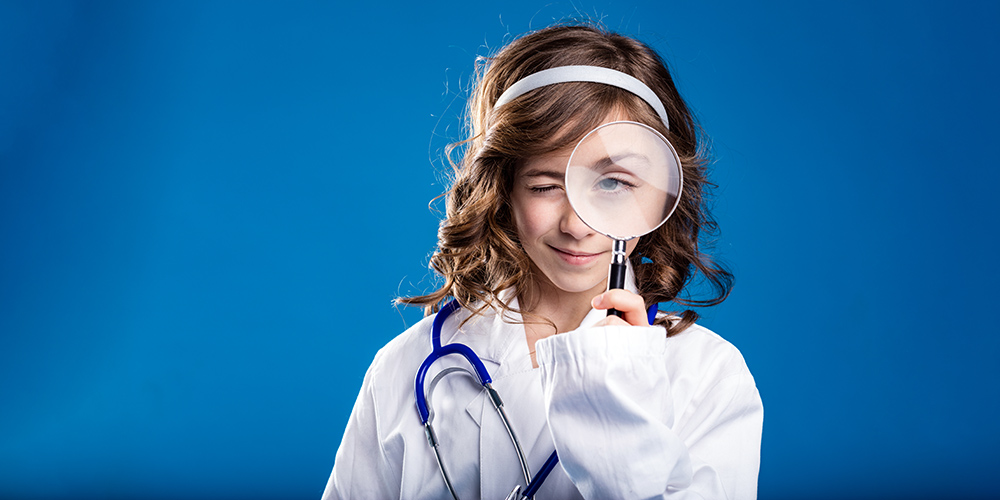 young girl dressed in doctor suit with magnifying glass