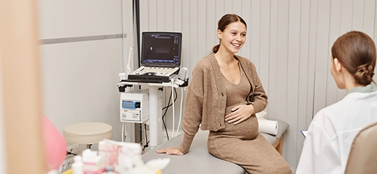 Pregnant woman talking with obstetrician at appointment.