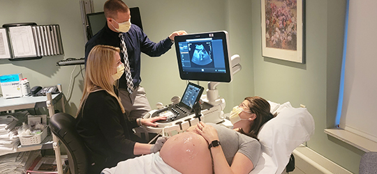 pregnant woman looking at sonogram with doctor