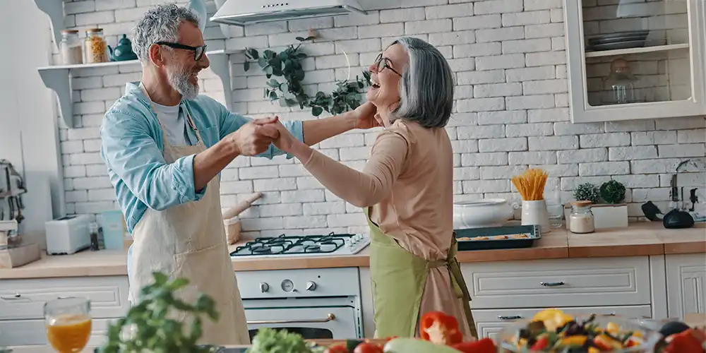 older couple dancing in kitchen while cooking