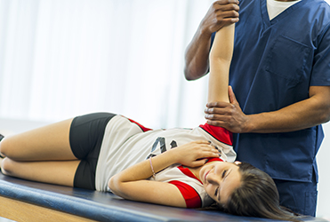 physical therapist working on teen's shoulder