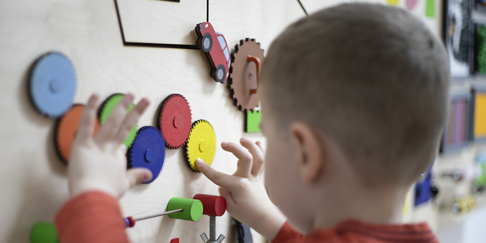 young boy playing with magnets on whiteboard