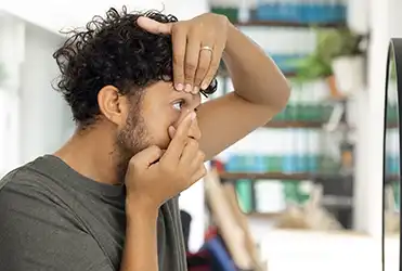 young man putting in contact lenses
