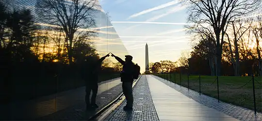 veteran looking at name on vietnam wall