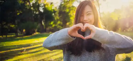 Teen making heart hands and smiling at camera