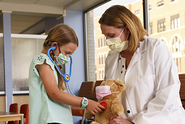 young girl and doctor listening to teddy bear visit