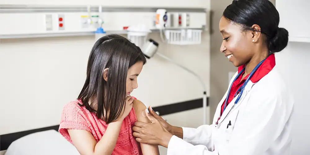 provider putting band-aid over vaccination site on young girl