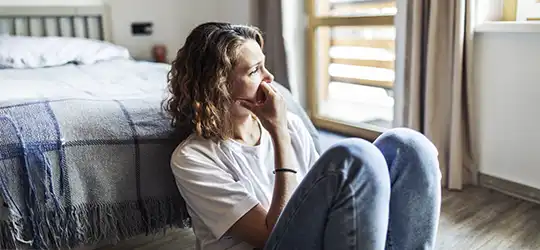 woman looking pensive outside of a window
