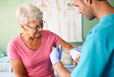 doctor wrapping senior woman's arm at an urgent care