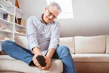 senior man holding foot in pain