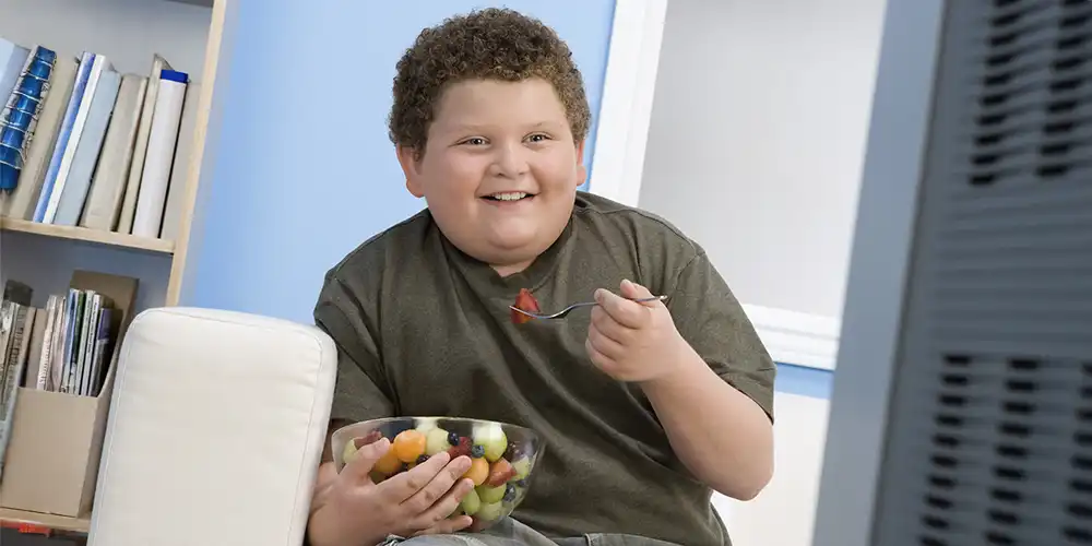 adolescent boy eating bowl of fruit