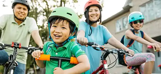 family on scooters and bikes wearing helmets