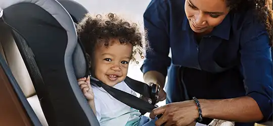 mom buckling toddler into car seat 